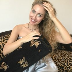 Mujer posando para la cámara delante de una cama Descripción generada automáticamente con confianza media